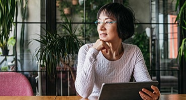 Woman holding tablet and thinking