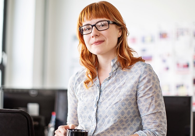 woman in office holds coffee mug