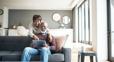 An older couple on a couch reviews documents