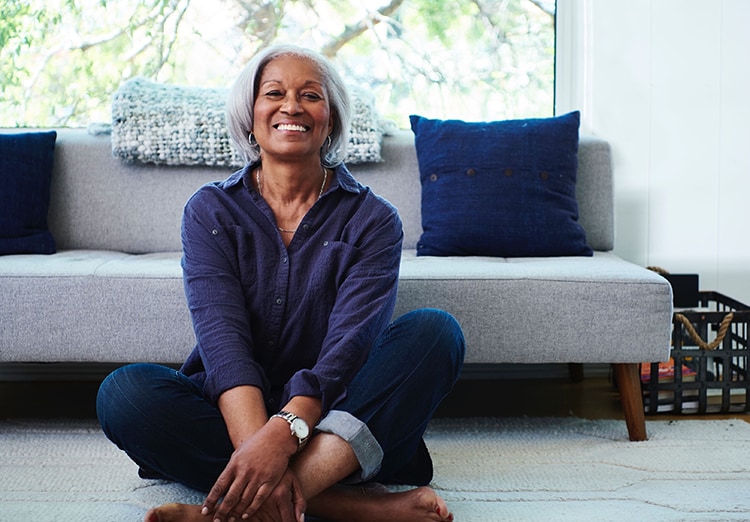 woman sits cross legged on floor in front of couch