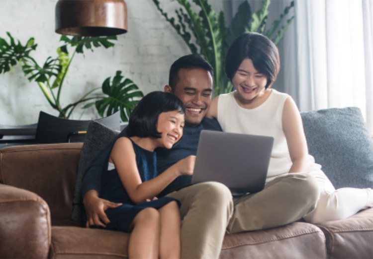 family sits on couch and looks at laptop