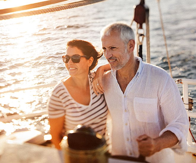 A couple sailing, while the sun is setting.