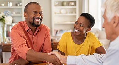 		Couple sits at table and smile as man shakes hands with another man