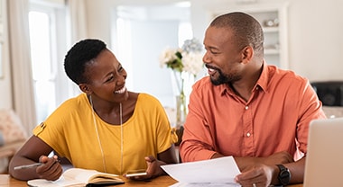 Couple smile at each other as they go through documents while sitting at a table