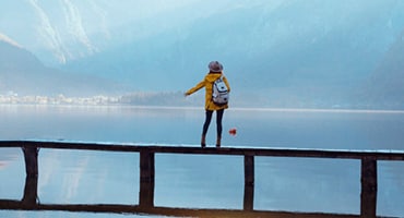 person stands on walking bridge looking out over body of water