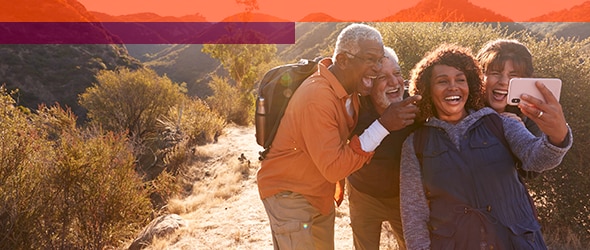 hikers on trail gather around a person holding a phone to take a selfie