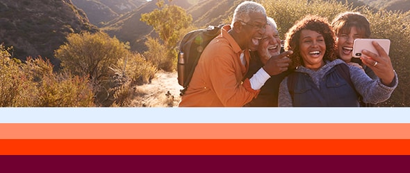 hikers on trail gather around a person holding a phone to take a selfie