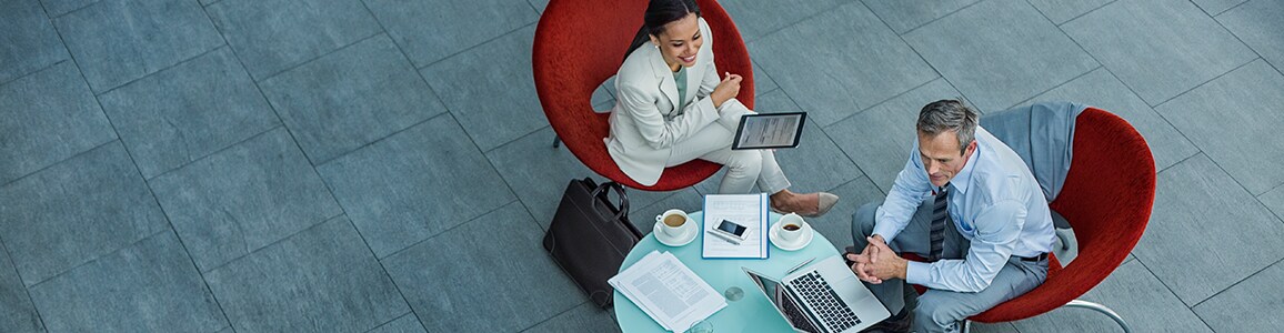 High angle view of 3 business people discussing strategy at coffee table in office