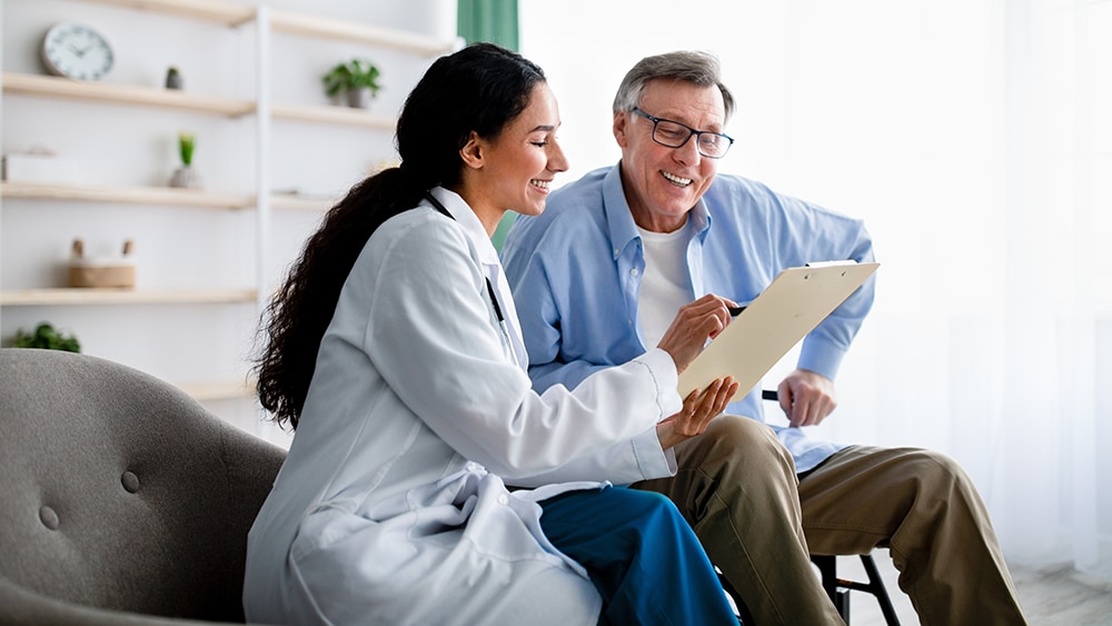 doctor sits with and goes over items on clipboard with patient