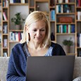 Woman works on laptop with shelves of books behind her