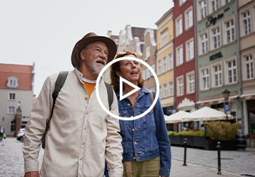 Older couple stand on cobblestoned street with buildings on either side