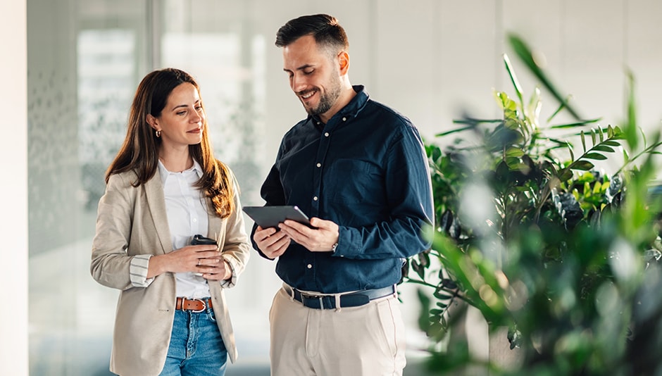 man and woman stand and look at electronic tablet