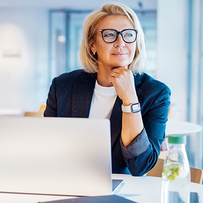 businesswoman sits in office with laptop open in front of her