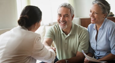 An older couple sitting across a desk from an advisor.