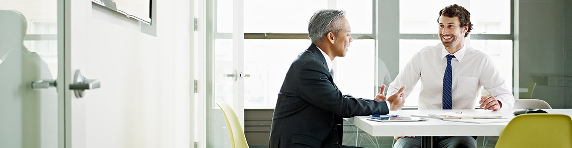 Two coworkers discussing project in office conference room smiling