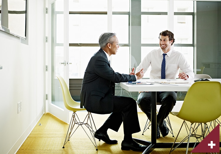 Two coworkers discussing project in office conference room smiling