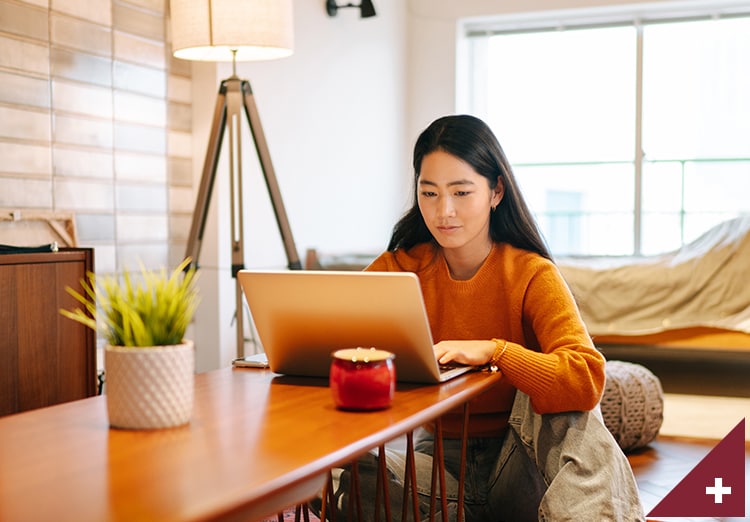 A woman works on a laptop at table