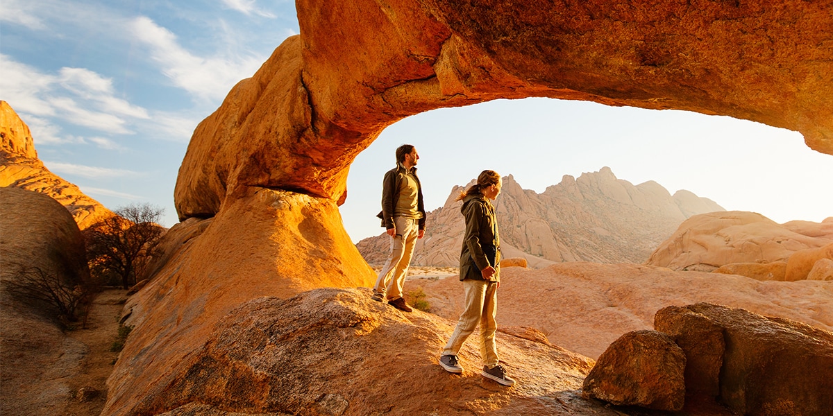 man and woman stand in front of rock formation