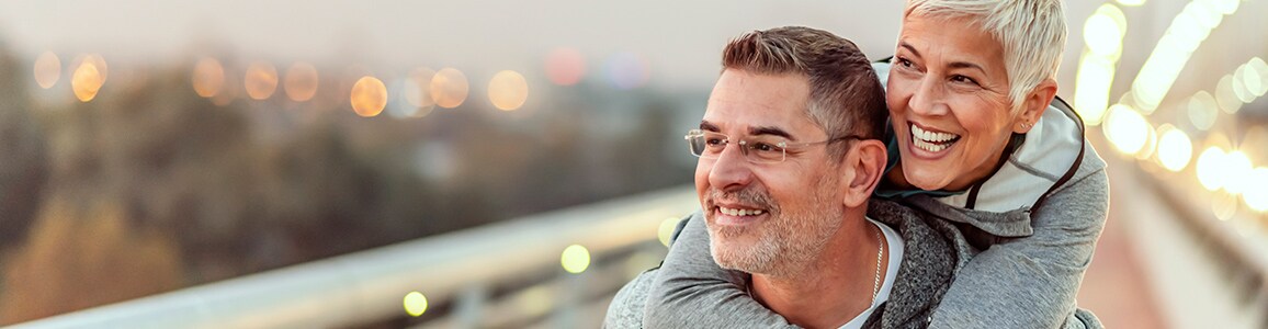 Man gives woman piggy back ride while smiling