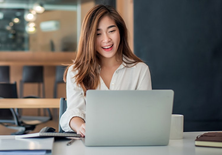 Happy young businesswoman sitting on her workplace in the office