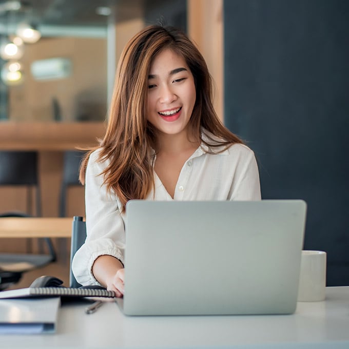 Happy young businesswoman sitting on her workplace in the office
