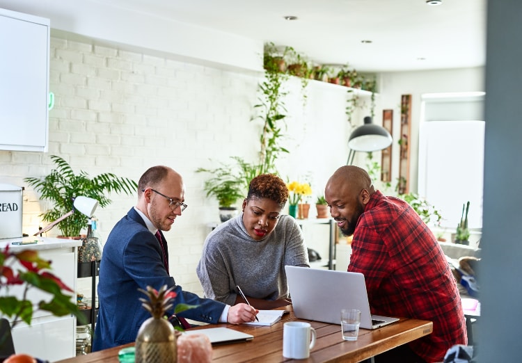 Advisor goes over forms with couple at kitchen table