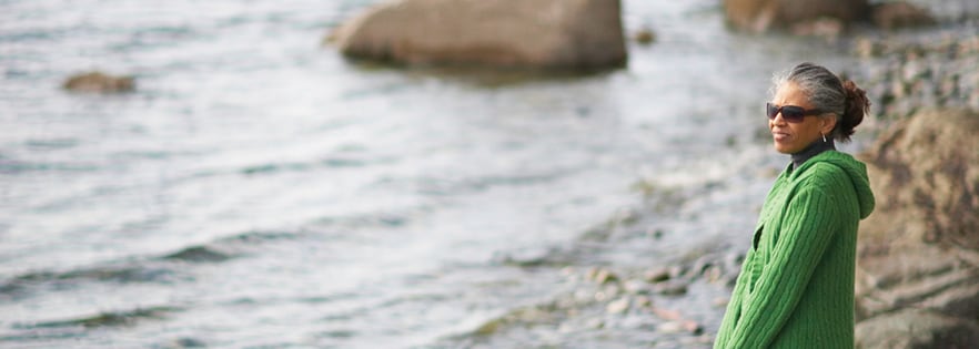 woman with sunglasses smiling by the water.