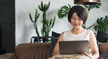 Woman sits on couch and works on laptop