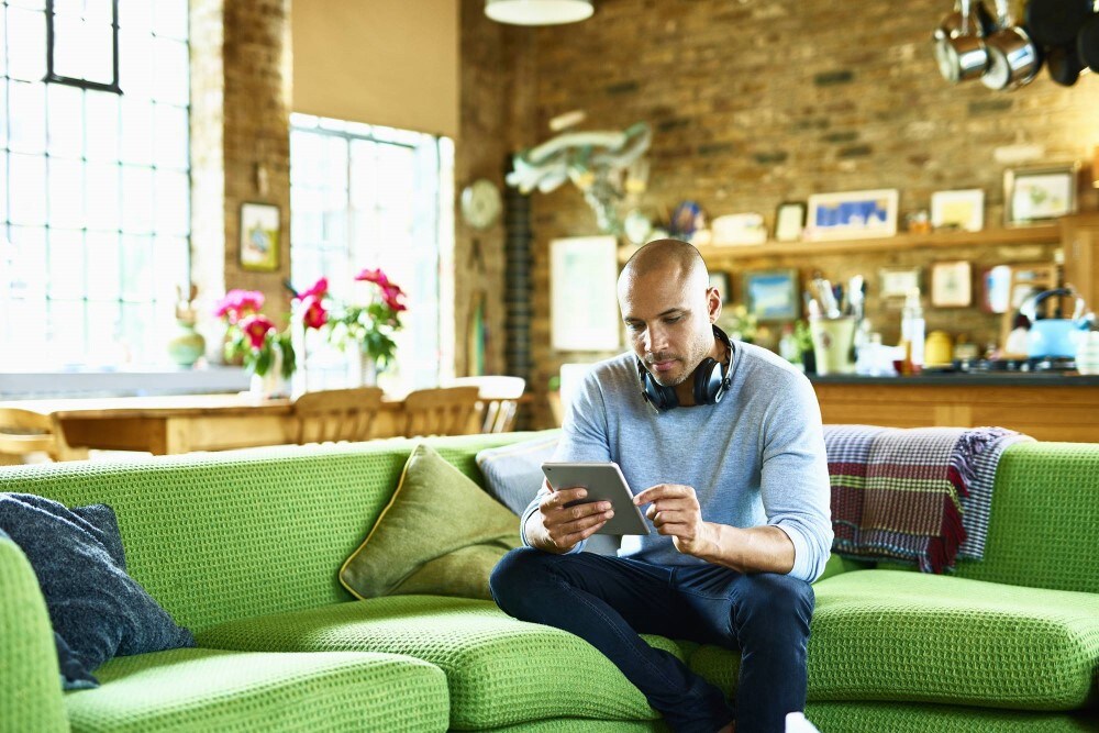 Man sits on couch and works on tablet