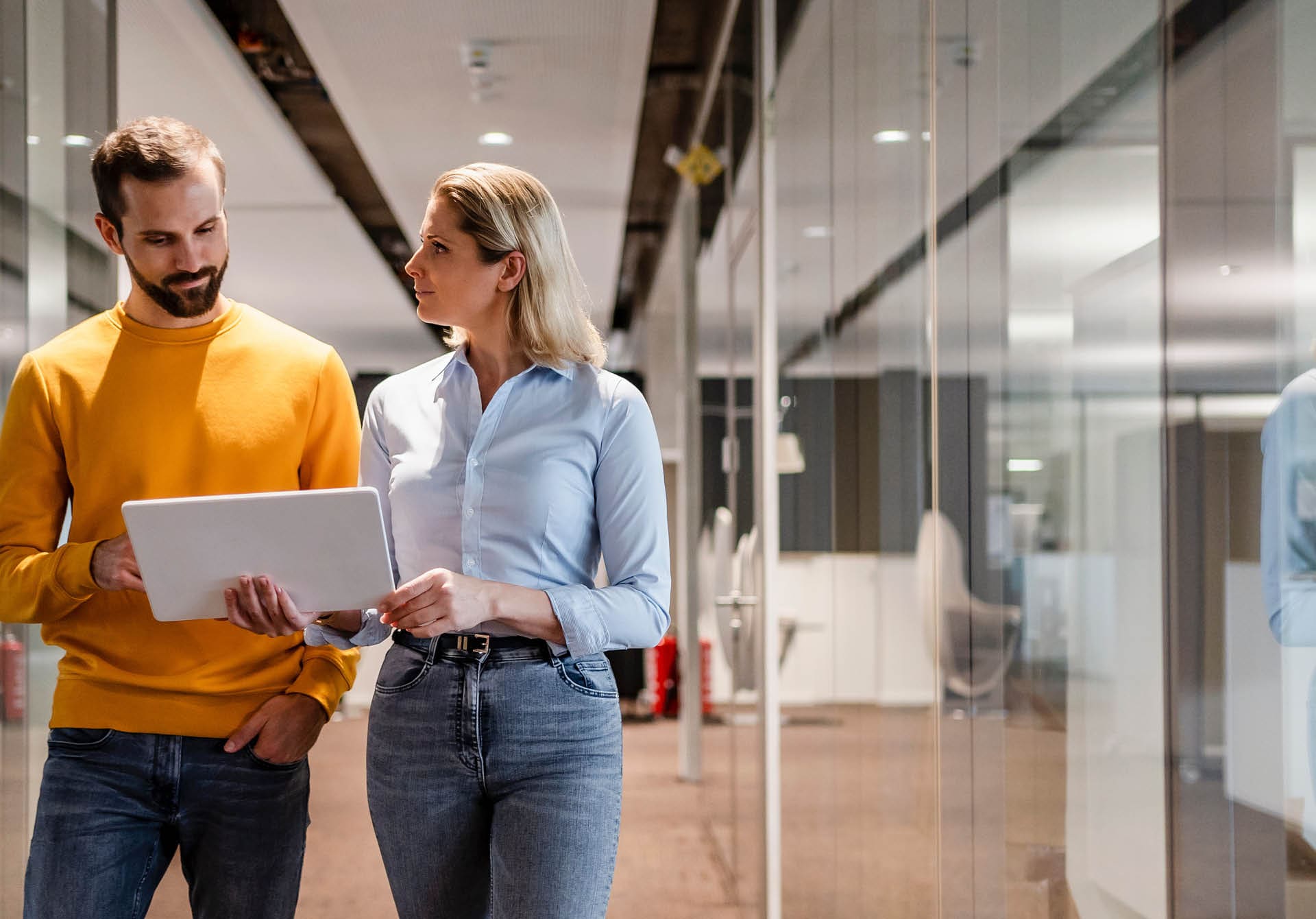 coworkers walking down a hall looking at a laptop