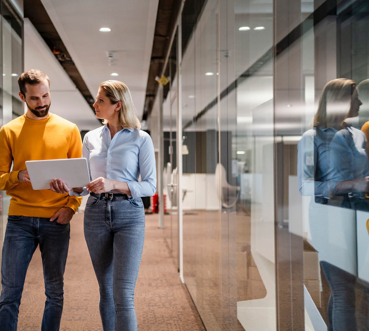 coworkers walking down a hall looking at a laptop