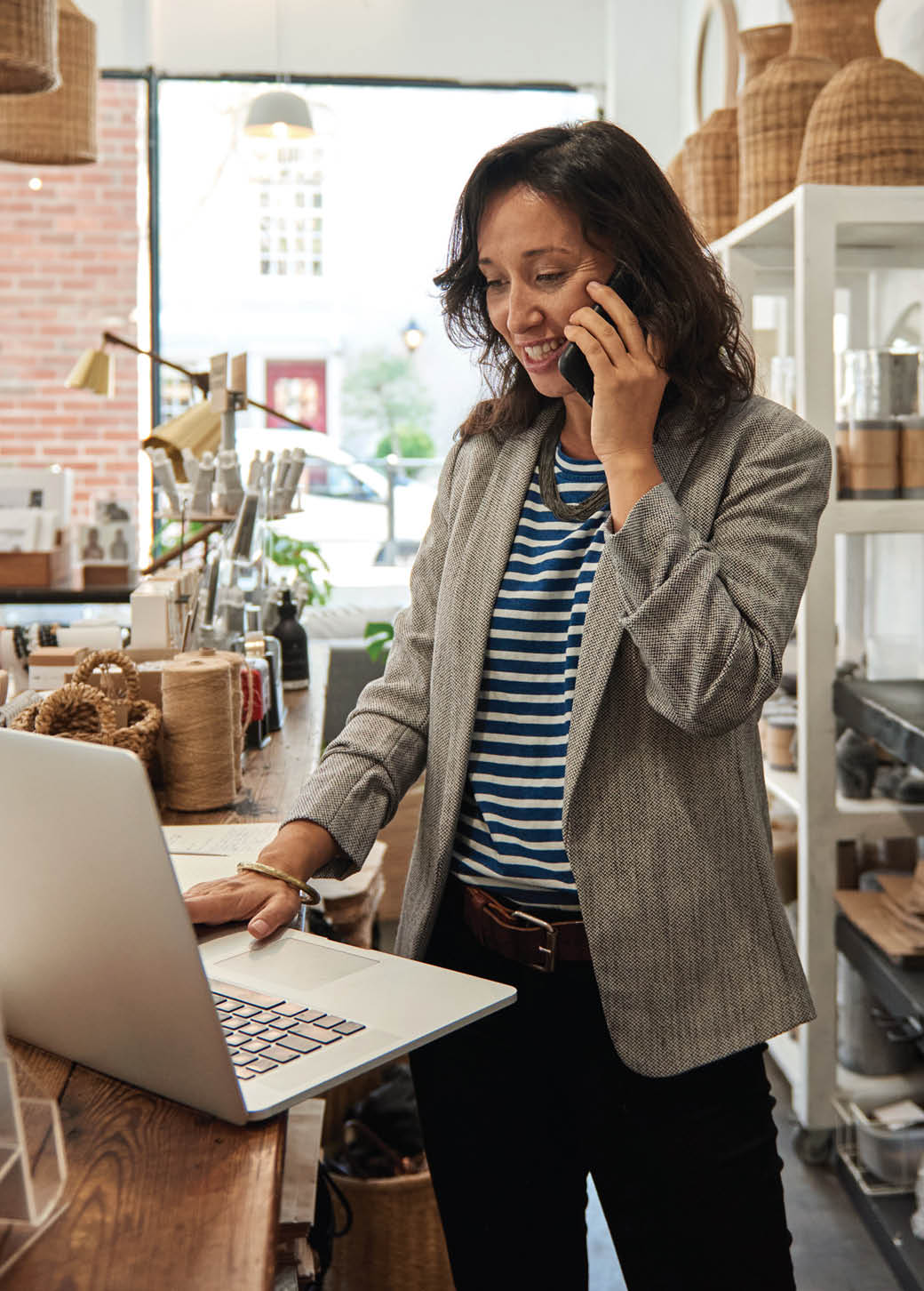 woman on mobile phone working in an office on a laptop