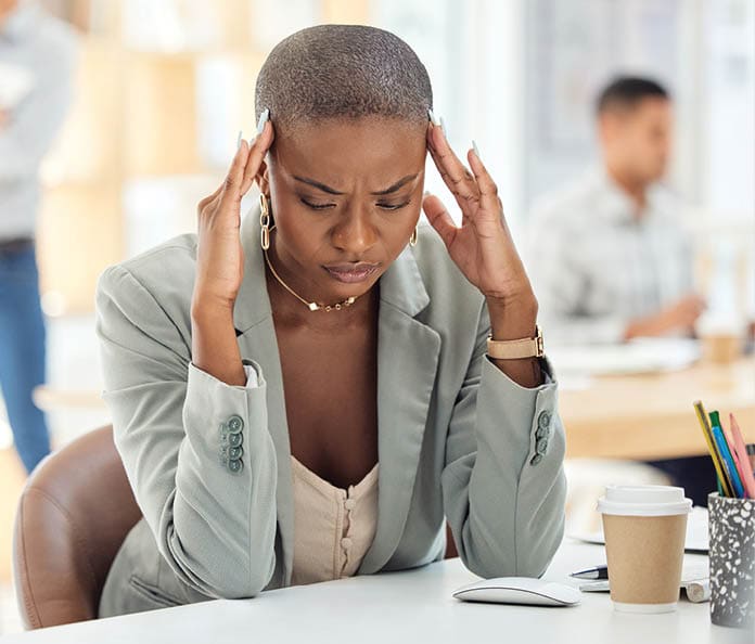 woman sitting at a desk rubbing her temples