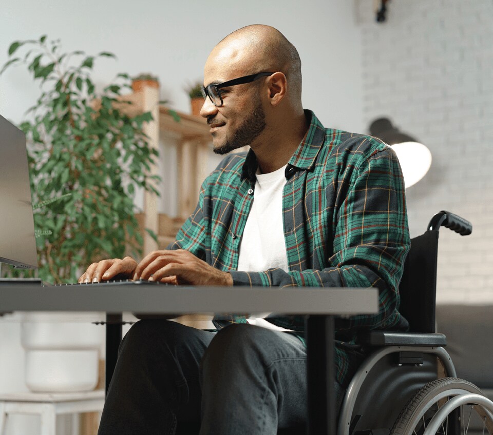 man in wheelchair working on a laptop at a desk