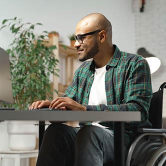 man in wheelchair working on a laptop at a desk