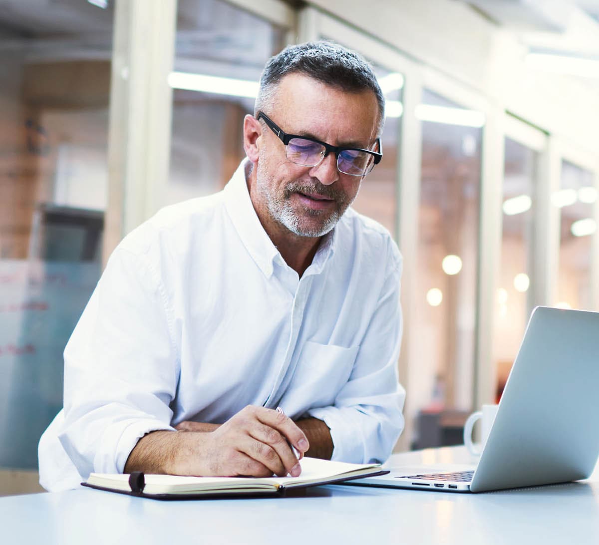 Experienced male skilled economist writing notes for delegate projects to his subordinates. University professor in eye glasses prepare for lectures after reading electronic book on laptop computer ; Shutterstock ID 492204427