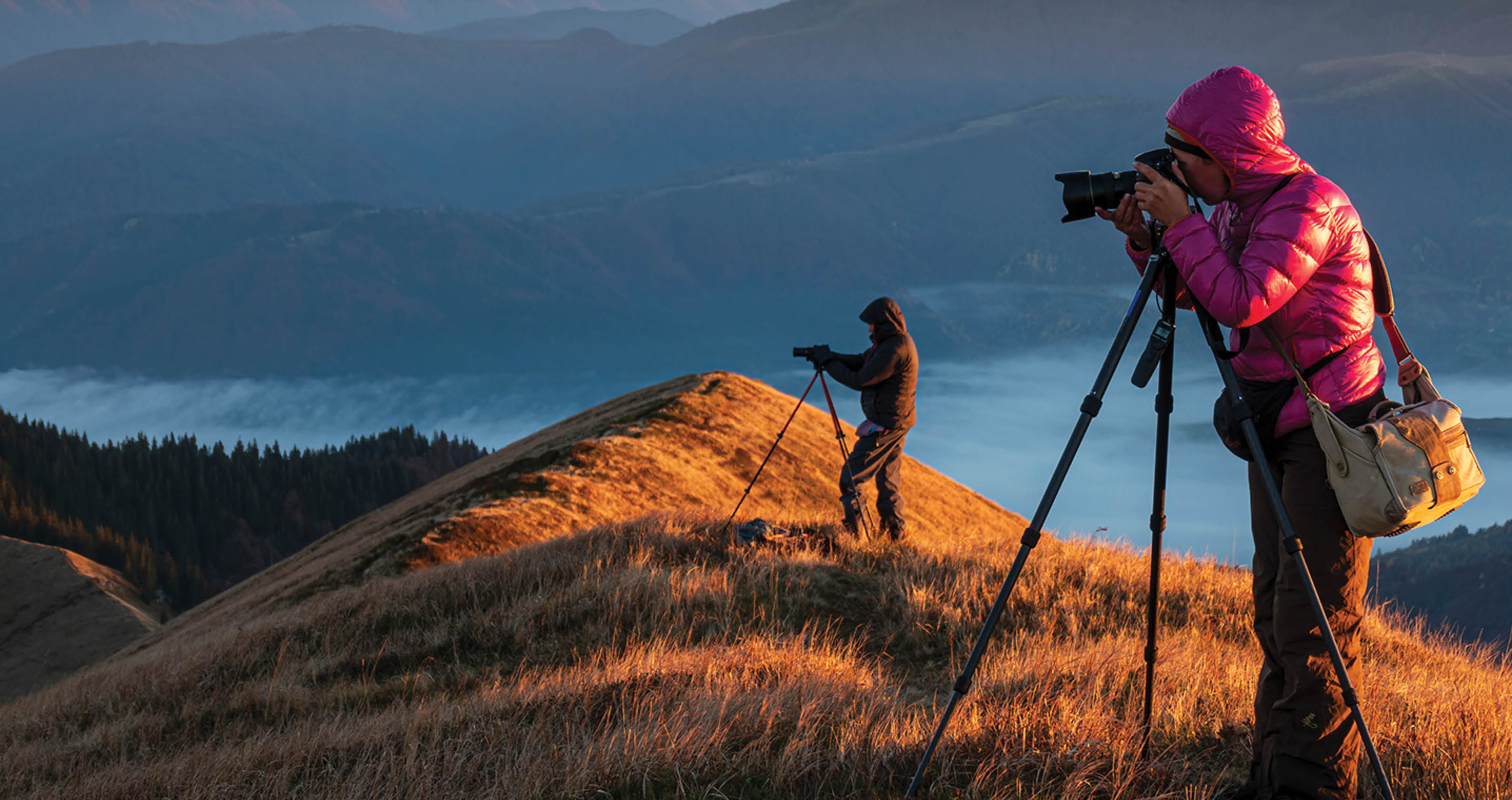 Landscape photographers with the tripods on the mountain top early in the morning. Creating exclusive photo content. Artists at work.