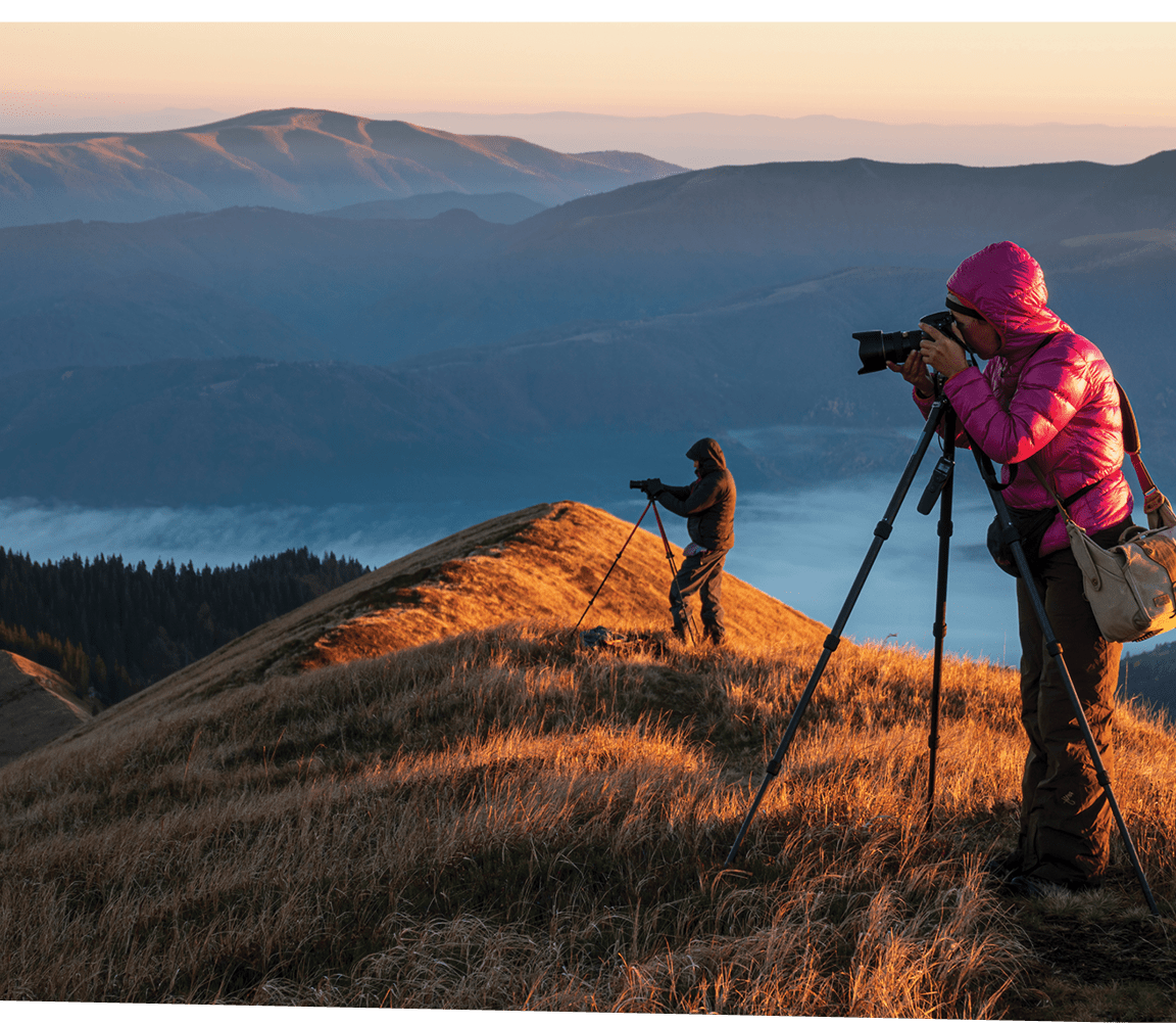 Landscape photographers with the tripods on the mountain top early in the morning. Creating exclusive photo content. Artists at work.