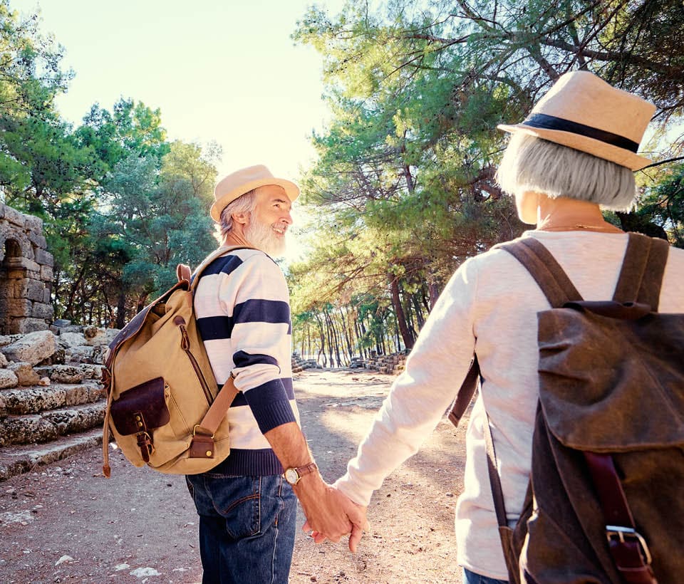 older couple holding hands while hiking