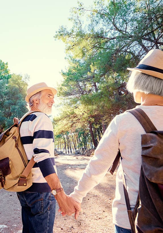 older couple holding hands while hiking