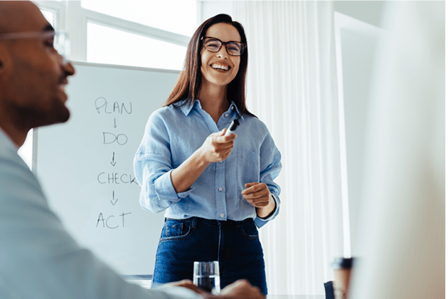 Happy business woman discussing ideas with her team during a meeting. Young business woman giving a presentation in an office.