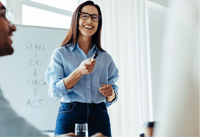 Happy business woman discussing ideas with her team during a meeting. Young business woman giving a presentation in an office.