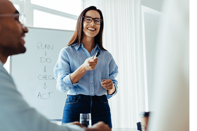 Happy business woman discussing ideas with her team during a meeting. Young business woman giving a presentation in an office.