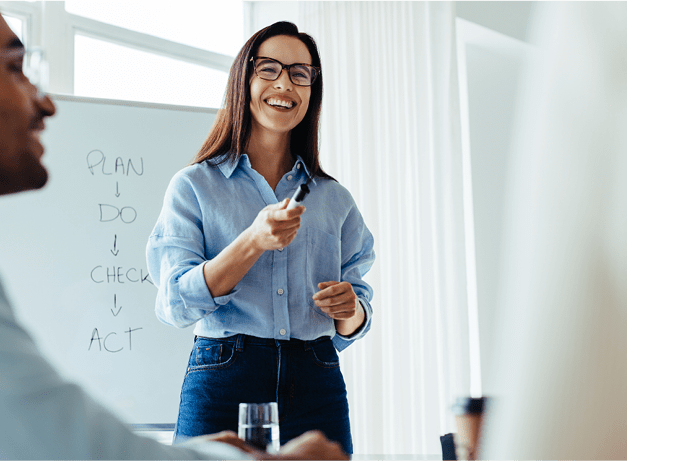 Happy business woman discussing ideas with her team during a meeting. Young business woman giving a presentation in an office.