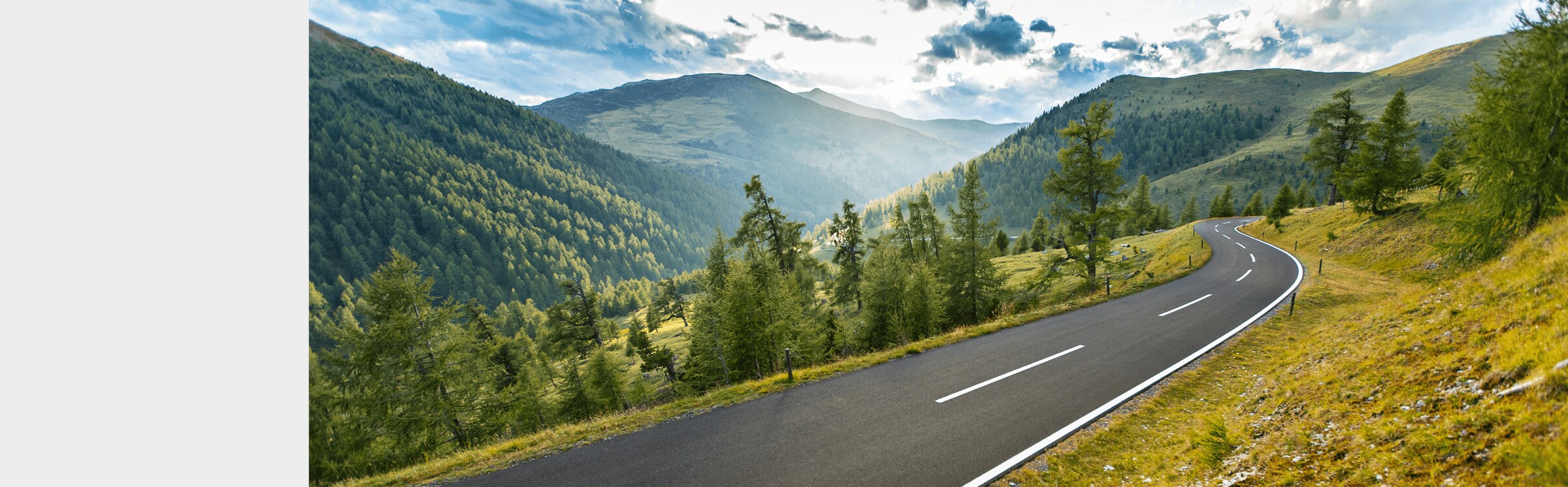 Open highway surrounded by tree filled mounatin valley