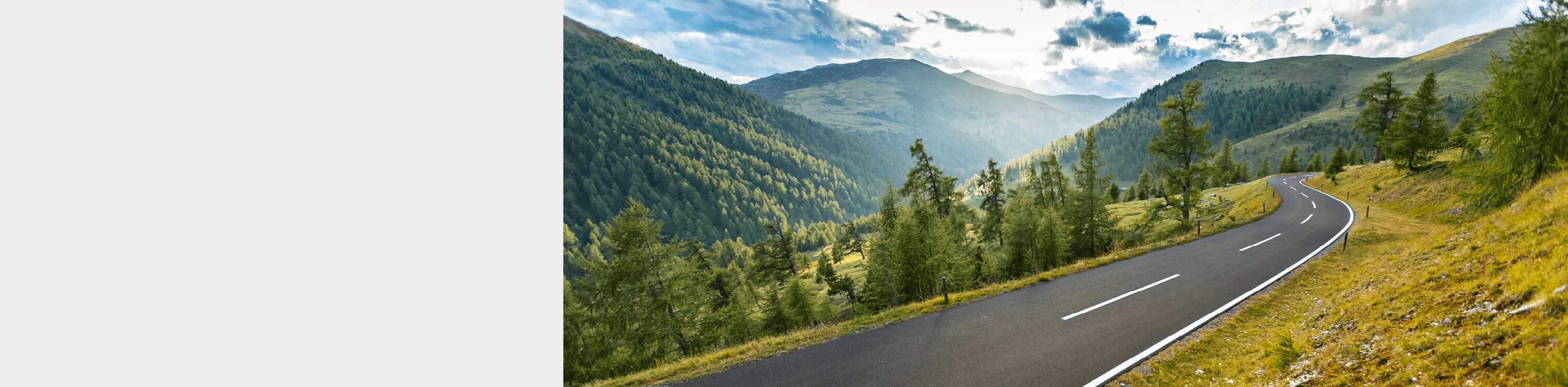 Open highway surrounded by tree filled mounatin valley