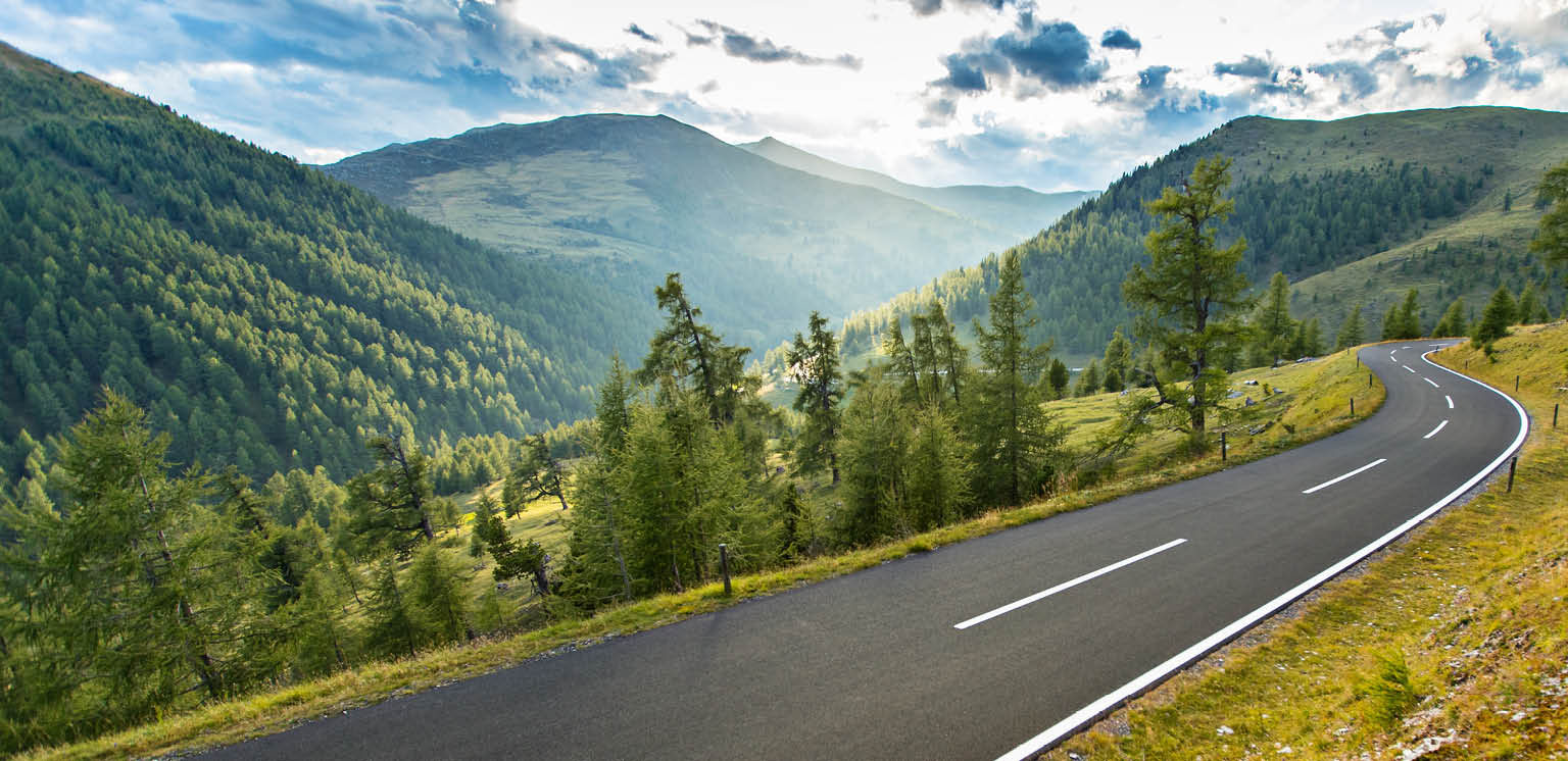 Open highway surrounded by tree filled mounatin valley