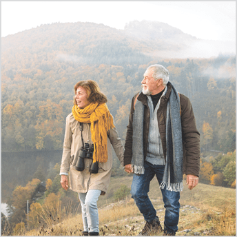 Image of older couple hiking with mountains in background.