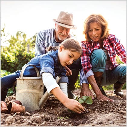 Image of older couple gardening with young girl.