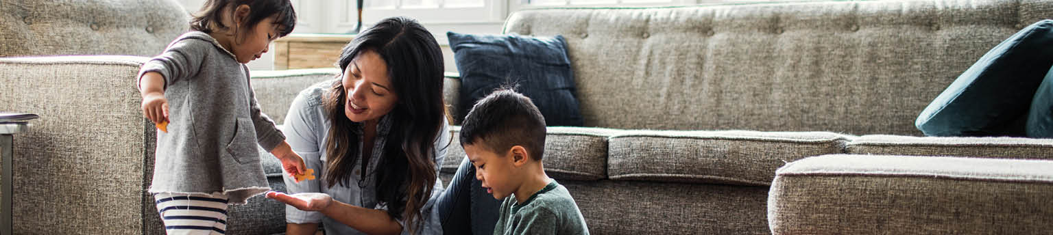 Image of mother playing on floor with children at home.
